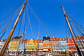 Boote und Menschen entlang des bunten Hafenviertels Nyhavn, mit Blick auf die Bootsmasten, Kopenhagen, Dänemark