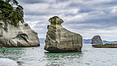 Die berühmte Cathedral Cove, die nur zu Fuß oder mit dem Boot zu erreichen ist, gehört zu den sehenswerten Orten auf dem Coromandel. Schwimmer genießen den Strand und spielen im Wasser, Waikato Region, Neuseeland