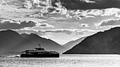 Yacht cruising Lake Wakatipu with dramatic lighting and silhouetted mountains in the background,Queenstown,South Island,New Zealand