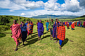 Maasai-Dorfbewohner führen eine Begrüßungsprozession für eine Gruppe von Touristen im Ngorongoro-Krater-Schutzgebiet, Tansania, durch