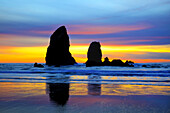 Silhouetted sea stacks along the Oregon coast at sunset with the sky displaying multiple glowing colors,Ecola State Park,Cannon Beach,Oregon,United States of America