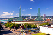 Oregon Convention Center in Portland, Oregon, mit Fußgängern und dem MAX-Zug auf den Gleisen und einem Blick auf die Stadtlandschaft und Skyline im Hintergrund, Portland, Oregon, Vereinigte Staaten von Amerika