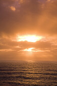 Glühende Sonne und Wolken bei Sonnenuntergang über dem Meer, Oregon, Vereinigte Staaten von Amerika