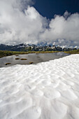Schnee im Vordergrund mit einer zerklüfteten Bergkette in der Ferne, Pazifischer Nordwesten