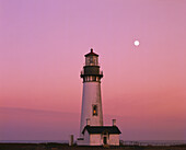 Yaquina Head Light vor einem leuchtend rosa Abendhimmel mit Vollmond,Oregon,Vereinigte Staaten von Amerika