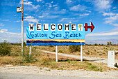 Willkommen am Salton Sea Beach Schild vor dem Hintergrund von Salton Sea und Bergen, Salton City, Kalifornien, Vereinigte Staaten von Amerika