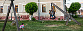 Local children playing on tyre swing in village playground,Transylvania,Dacia,Brasov County,Romania