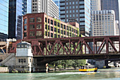 The Chicago Water Taxi navigates the Chicago River under Lake Street Bridge and skyscrapers.,Chicago,Illinois