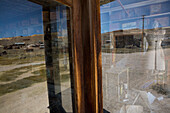The interior of an abandoned general store and the surrounding landscape reflected in a store window.,Bodie State Historic Park,Bridgeport,California