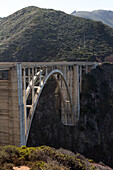 Several people sitting and sightseeing atop the Bixby Creek Bridge,a concrete,open-spandrel arch bridge,on the Pacific Coast Highway.,Bixby Creek Bridge,Pacific Coast Highway,California