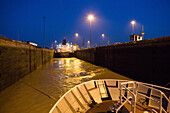 A large shipping vessel and expedition cruise ship are guided through the Pedro Miguel Locks in the Panama Canal.,Panama