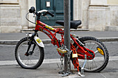 Heavily locked damaged kids bike on pole,Rome,Italy