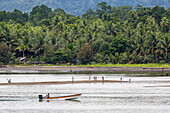 Motorboot fährt an spielenden Kindern auf einer Sandbank in Morobe Bay, Provinz Morobe, Papua-Neuguinea, Morobe Bay, Provinz Morobe, Papua-Neuguinea, vorbei