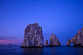 Ein Kreuzfahrtschiff nähert sich in der Morgendämmerung den Felsformationen des Land's End Arch.