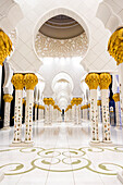Eine Nachtansicht eines der verzierten Korridore in der Großen Moschee in Abu Dhabi City, Vereinigte Arabische Emirate. Die Beschreibung lautet: "Wenn es wie Gold aussieht, ist es echtes Gold", Abu Dhabi, Vereinigte Arabische Emirate