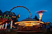 Motion blur of illuminated rides at a traveling carnival at dusk,Yelm,Washington,United States of America