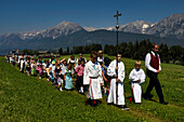 Der Festzug zum Herz-Jesu-Fest betritt eine große Wiese im Karwendelgebirge, Österreich.