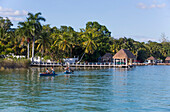 Docks an der Lagune von Bacalar, Mexiko, mit Touristen, die Freizeitaktivitäten genießen, Bacalar, Staat Quintana Roo, Mexiko