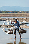 A man carries baskets of rice in a farming community in Southern Cambodia,Kampot,Cambodia