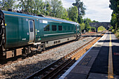 Grüner Personenzug auf den Gleisen eines Bahnhofs in den Cotswolds, UK, Ampney Crucis, Cotswolds, England