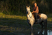 Woman sitting atop her horse in the late day sunshine creating a perfect portrait,Saintes-Maries-de-la-Mer,France