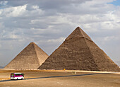 Touristenbus nähert sich zwei der Großen Pyramiden von Gizeh, Gizeh, Ägypten