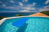 Blaues Floß schwimmt in einem Pool mit Blick auf das Karibische Meer, Saint John, U.S. Virgin Islands