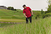 Mann sucht nach verlorenem Golfball auf dem Golfplatz