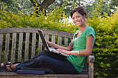 University Student Sitting on a Bench Using a Laptop Computer