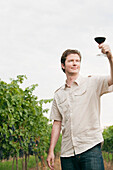 Mann im Weinberg prüft ein Glas Wein