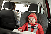 Baby im Autositz mit fahrender Mutter