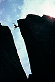 Silhouette eines Wanderers, der über einen Abgrund springt Val David, Quebec, Kanada