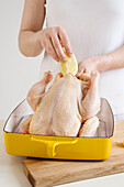 Frau füllt Hähnchen mit Zitrone und Knoblauch
