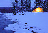 Glühendes Zelt am Fluss im Winter Kananaskis Country, Alberta Kanada