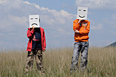 Boys in Field holding Drawn Facial Expressions