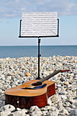 Notenständer und Gitarre am Strand