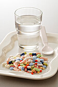 Verschiedene Medikamente und ein Glas Wasser