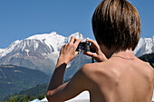 Rückenansicht eines Jungen beim Fotografieren von Bergen, Alpen, Frankreich