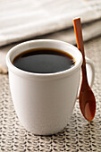 Nahaufnahme einer Tasse mit schwarzem Kaffee und Löffel