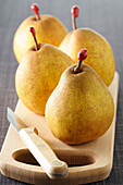 Close-up of Four Pears on Cutting Board with Knife on Grey Background,Studio Shot