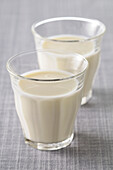 Zwei Gläser Milch auf grauem Hintergrund, Studioaufnahme