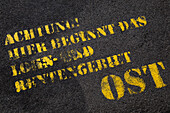 Großaufnahme von deutschem Text auf gepflasterter Straße (Achtung, hier beginnt der Bereich Lohn und Rente Ost),Berlin,Deutschland