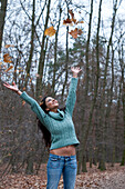 Frau wirft Herbstblätter in die Luft