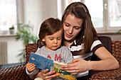 Mädchen im Teenageralter liest kleinem Jungen ein Buch vor,Mannheim,Baden-Württemberg,Deutschland