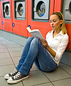 Woman Reading a Book in Laundromat