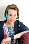 Nahaufnahme eines Teenagers mit Kopfhörern, der Musik hört und lächelt, Studioaufnahme vor weißem Hintergrund