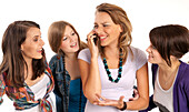 Four,young women laughing and looking at each other,one young woman using cell phone,studio shot on white background