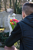 Teenager in front of Grave Stones with Tulips in Cemetery