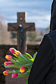 Teenager mit Tulpen vor den Grabsteinen auf dem Friedhof