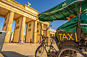 Blick auf Brandenburger Tor, Rikscha und Besucher auf dem Platz des 18. März an einem sonnigen Tag,Mitte,Berlin,Deutschland,Europa